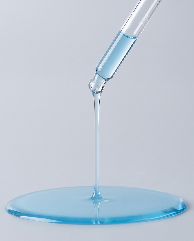 Blue serum running from a glass dropper